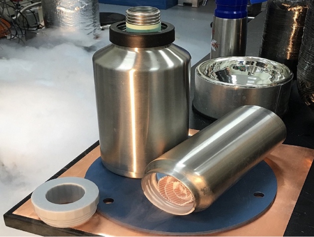 Polished metal cryogenic storage vessels on a workbench